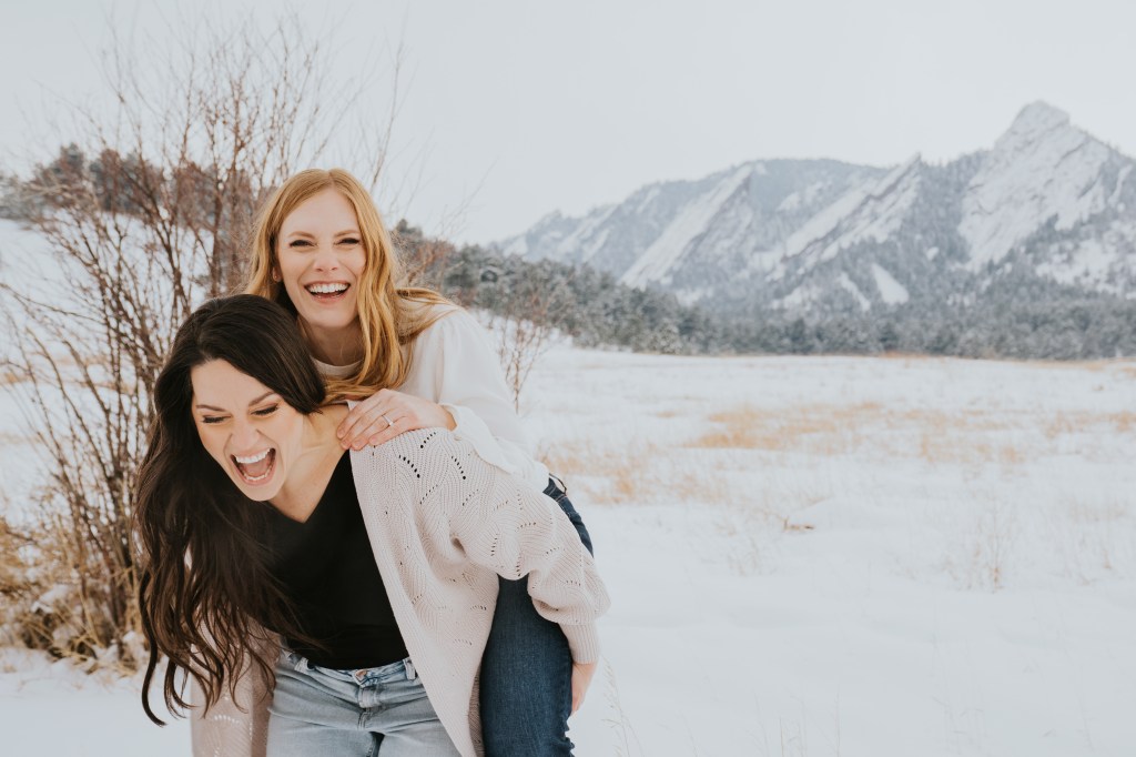 Kate Ebert and her wife pose, laughing in the foothills of the Boulder flatiron mountains.